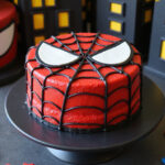 Finished Spiderman cake with detailed web design and character embellishments, ready for a superhero-themed party.
