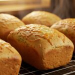 Delicious Copycat Subway Italian Herb & Cheese Bread loaves cooling on a rack, featuring a golden crust and melted cheese.